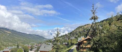 A mountain village with traditional wooden houses, a clear sky, and a valley below.