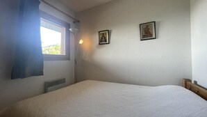 A bedroom with a single bed, a window with a curtain, a radiator, and two framed pictures on the wall. - 250m from ski slopes, 5th floor, view ski slopes, swimming pool, balcony, tv, ski locker, 32m² (Méribel - Les Allues)