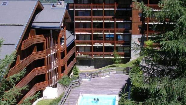 A hotel with a pool, wooden balconies, and a view of the surrounding greenery. - 250m from ski slopes, 5th floor, view ski slopes, swimming pool, balcony, tv, ski locker, 32m² (Méribel - Les Allues)
