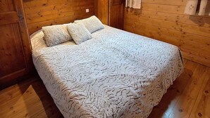 A wooden room with a bed, a window with curtains, and a ceiling light. - 100m from ski slopes, 3rd floor, view mountain, balcony, tv, 43m², Méribel (Méribel - Les Allues)