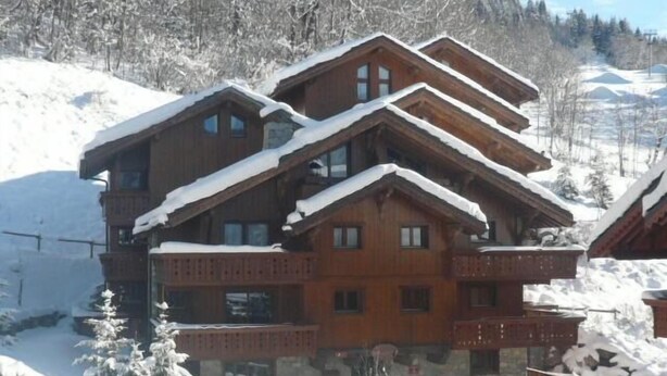 A multi-story wooden chalet with balconies, surrounded by snow-covered trees and a mountainous backdrop. - 100m from ski slopes, 3rd floor, view mountain, balcony, tv, 43m², M éribel (Méribel - Les Allues)