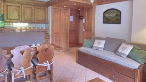 A cozy room with wooden furniture, a sofa, a dining table with chairs, and a kitchen area. - 100m from ski slopes, 3rd floor, view mountain, balcony, tv, 43m², Méribel (Méribel - Les Allues)