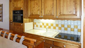 A kitchen with wooden cabinets, a tiled backsplash, and a built-in oven. - 100m from ski slopes, 3rd floor, view mountain, balcony, tv, 43m², Méribel (Méribel - Les Allues)