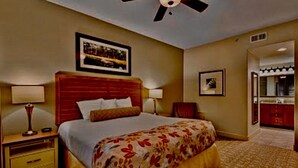Ein Hotelzimmer mit einem großen Bett, zwei Nachttischen mit Lampen, einem Deckenventilator und einem gerahmten Bild an der Wand.