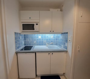 A compact kitchen with a microwave, sink, and cabinets.