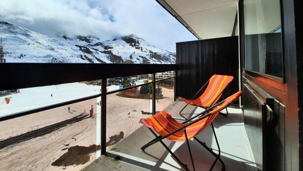 Varanda com vista para uma montanha nevada e céu limpo.