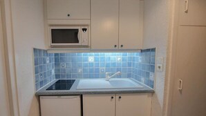 Uma cozinha compacta com micro-ondas, pia e armários.