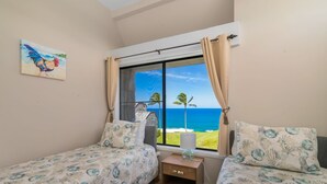 Une chambre avec deux lits, une table de chevet et une fenêtre donnant sur l’océan.