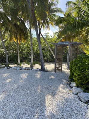 Un sentier de gravier mène à un panneau indicateur en bois portant l’inscription « Coconut Grove ».