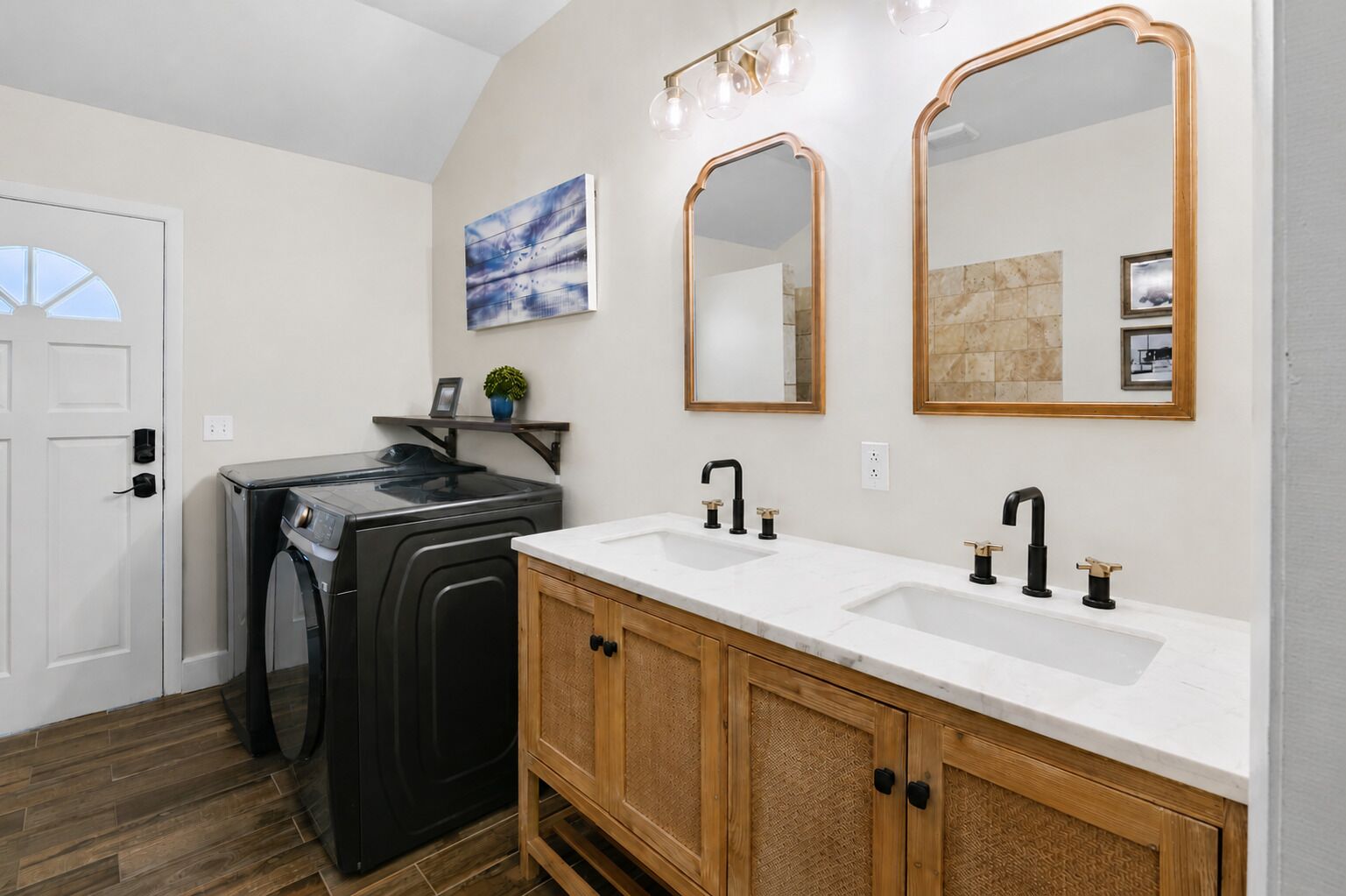 A bathroom with a double sink vanity, two wall-mounted mirrors, a towel rack, and a laundry machine.