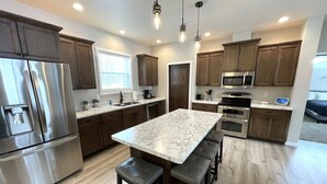 A modern kitchen with stainless steel appliances, a marble island, and wooden cabinets. - Serenity Now @ Spring Brook Resort (Wisconsin Dells)