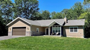 A two-story house with a garage, a covered porch, and a stone foundation. - Serenity Now @ Spring Brook Resort (Wisconsin Dells)
