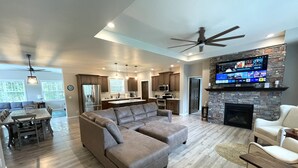 A spacious living room with a large sectional sofa, a fireplace, a dining area with a table and chairs, and a kitchen with modern appliances. - Serenity Now @ Spring Brook Resort (Wisconsin Dells)