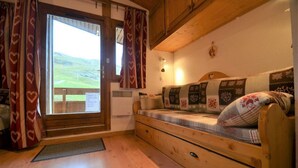 Una camera accogliente con una panca di legno, una finestra con tende e vista sull'esterno.