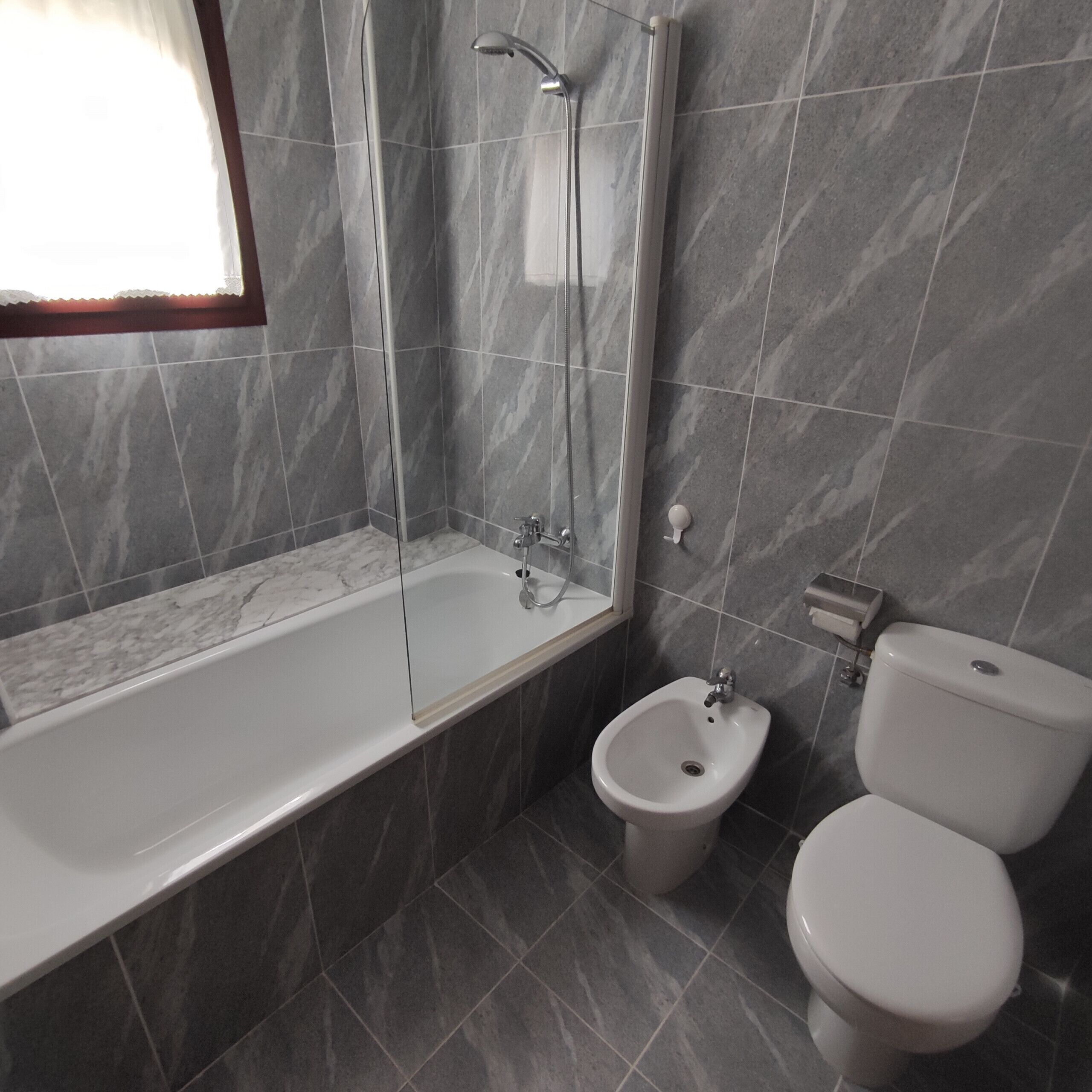 A modern bathroom with a bathtub, a bidet, and a toilet.