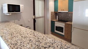 A compact kitchen with a microwave, oven, and refrigerator. - Apartamento Da Vinci 5 Inmomart (Peñiscola)