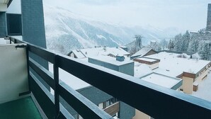 Un balcon offrant une vue sur des bâtiments et des montagnes enneigés.