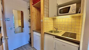 Une cuisine compacte équipée d’un four à micro-ondes, d’un évier et d’un petit réfrigérateur.