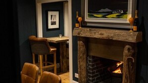 A cozy room with a fireplace, a framed picture above it, and a table with chairs. - 12 Loch View PF Kenmore (Aberfeldy)