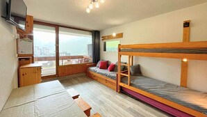 A compact room with bunk beds, a small desk, and a window offering a view. - 10m from ski slopes, 8th floor, balcony, tv, 24m², Les Menuires (Les Menuires)