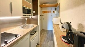 A compact kitchen with a sink, microwave, and a compact refrigerator. - 10m from ski slopes, 8th floor, balcony, tv, 24m², Les Menuires (Les Menuires)