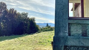 A stone structure with a large arched window, a grassy field, and a mountain in the background. - Château de La Tisnère on the outskirts of Pau (Gelos)