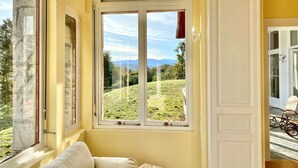 A room with a large arched window offering a view of a grassy landscape and mountains. - Château de La Tisnère on the outskirts of Pau (Gelos)
