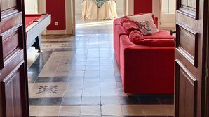 A room with a red sofa, a pool table, and a view of a balcony with a table and chairs. - Château de La Tisnère on the outskirts of Pau (Gelos)