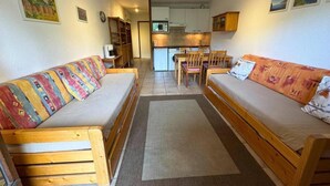 A compact room with two wooden sofas, a small kitchen area, and a dining table. - 1st floor, view ski slopes, balcony, ski locker, 33m², Saint Martin de Belleville (Saint-Martin-de-Belleville)