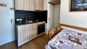 A compact kitchen with wooden cabinets, a black countertop, and a built-in oven.