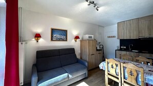 A compact living space with a sofa, a dining table, and a kitchenette.