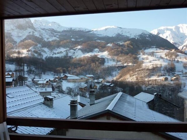 A view of a snow-covered mountain range with a village in the valley below.