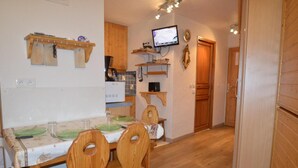 Una cocina con armarios de madera, una mesa de comedor con platos verdes y un televisor montado en la pared.