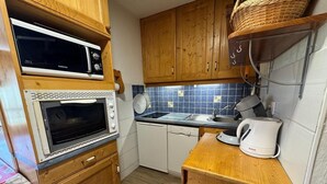 Cocina compacta con armarios de madera, microondas, tostadora y cafetera.
