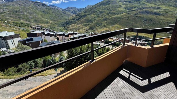 Un balcón con vistas a un paisaje montañoso y un pequeño pueblo abajo.