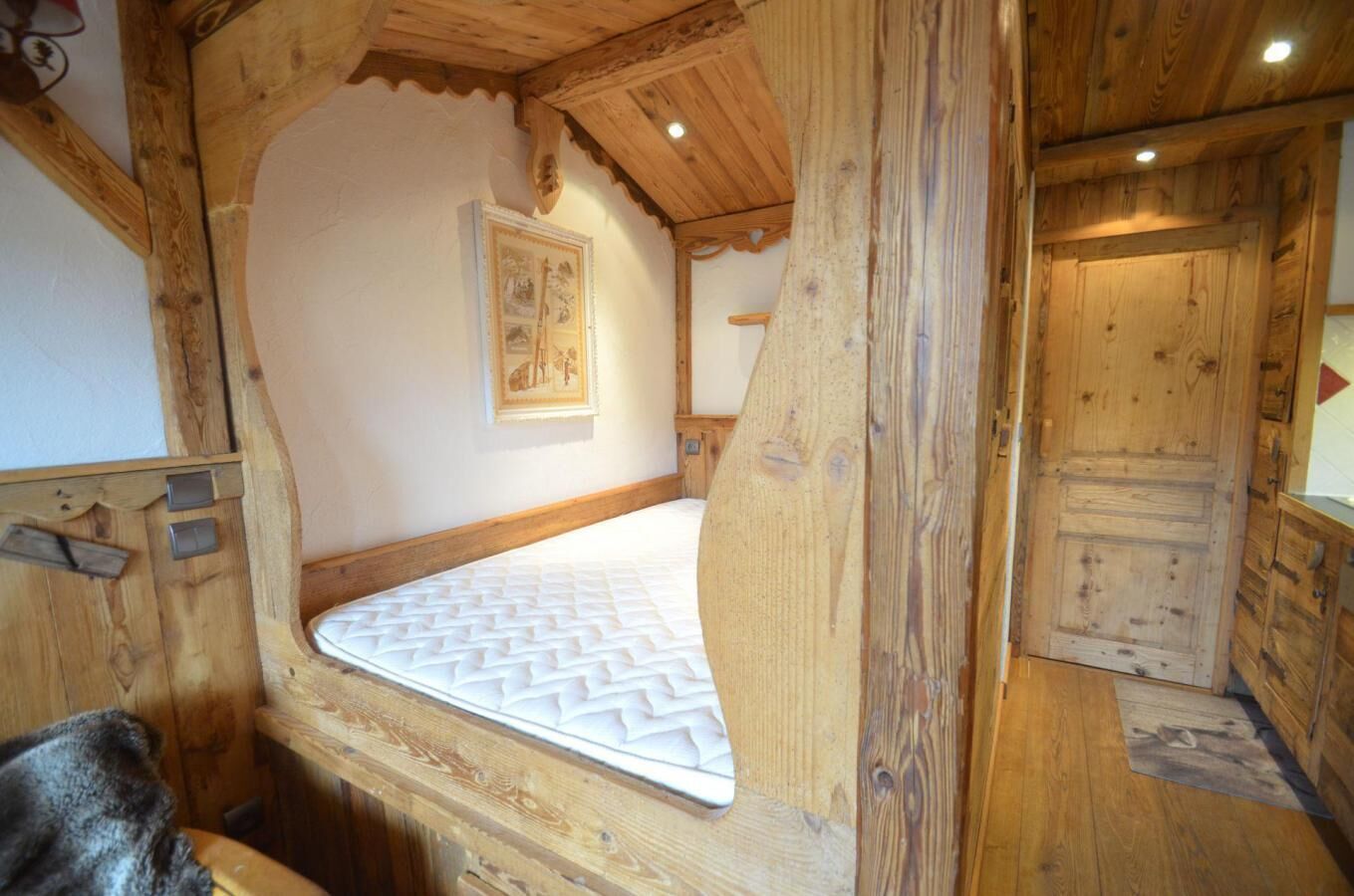 A wooden cabin room with a bed, wooden walls, and a door.