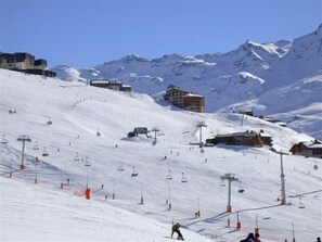 A snow-covered ski slope with ski lifts, buildings, and mountains in the background. - 100m from shops, 7th floor, balcony, tv, 24m², Les Menuires (Les Menuires)