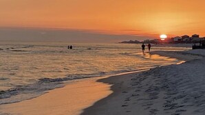 Una spiaggia al tramonto con persone che camminano sulla riva.