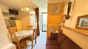 A compact living space with a dining area, a sofa, a TV, and a kitchen area.