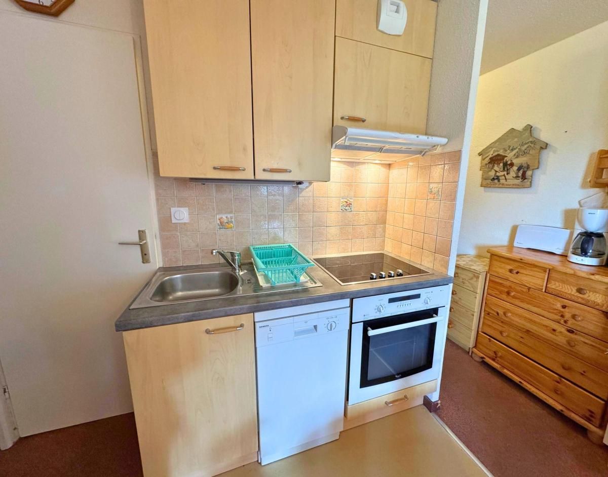A compact kitchen with wooden cabinets, a dishwasher, an oven, and a sink.