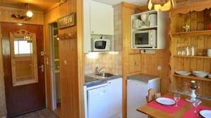 Una cucina compatta con mobili in legno, un forno a microonde, un lavello e un piccolo frigorifero.
