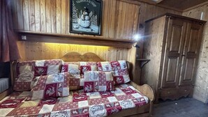 Una stanza accogliente in legno con un letto, una coperta trapuntata e cuscini, una testiera in legno e un quadro appeso alla parete.