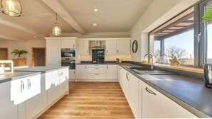 Een moderne keuken met witte kasten, een centraal eiland en een groot raam dat voor natuurlijk licht zorgt.