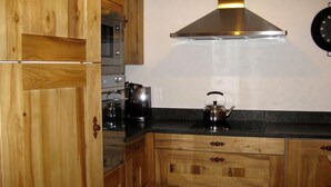 Une cuisine avec des meubles en bois, une hotte en acier inoxydable, une bouilloire et un four à micro-ondes.