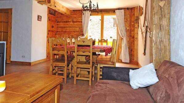 Una habitación acogedora con una mesa de comedor de madera, sillas, un sofá y un televisor.