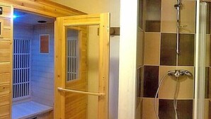 Un sauna avec une porte en bois, un banc et un espace douche doté d’une porte en verre.