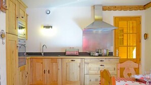 A kitchen with wooden cabinets, a stainless steel range hood, a toaster, and a window with a view of the outside. - Chalet, sauna, balcony, fireplace or stove, parking, tv, ski locker, 140m², Les Menuires (Saint-Martin-de-Belleville)