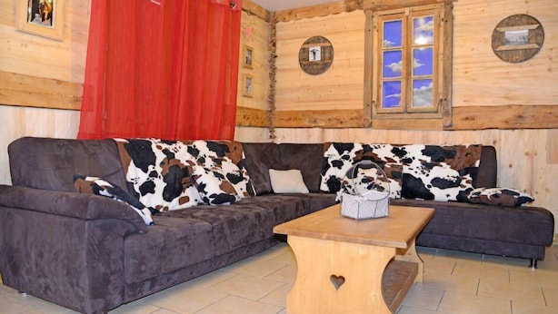 A cozy room with a dark grey sofa, a wooden coffee table, and a red curtain. - Chalet, sauna, balcony, fireplace or stove, parking, tv, ski locker, 140m², Les Menuires (Saint-Martin-de-Belleville)