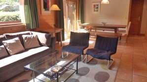 A cozy living room with a sofa, two armchairs, a glass coffee table, and a dining table with chairs. - 2nd floor, terrace, tv, ski locker, 71m², Méribel (Méribel - Les Allues)