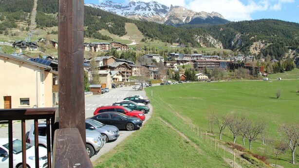 Une station de montagne dotée d’un parking, de bâtiments et offrant une vue sur des montagnes enneigées.